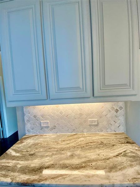Close-up of cabinets & granite tied together with decorative mosaic tile backsplash