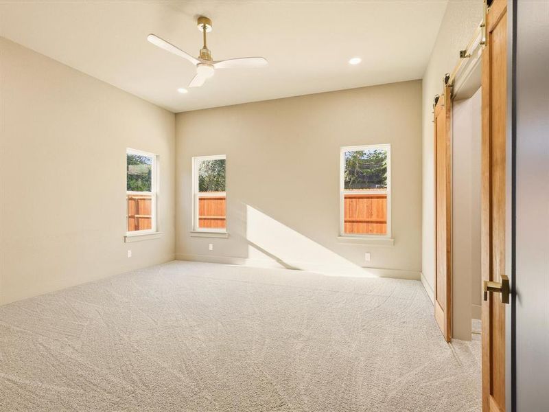 Empty room with a barn door, carpet flooring, recessed lighting, and a ceiling fan