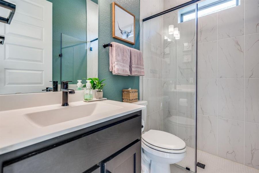 Full bathroom with a marble finish shower, vanity, and a textured wall