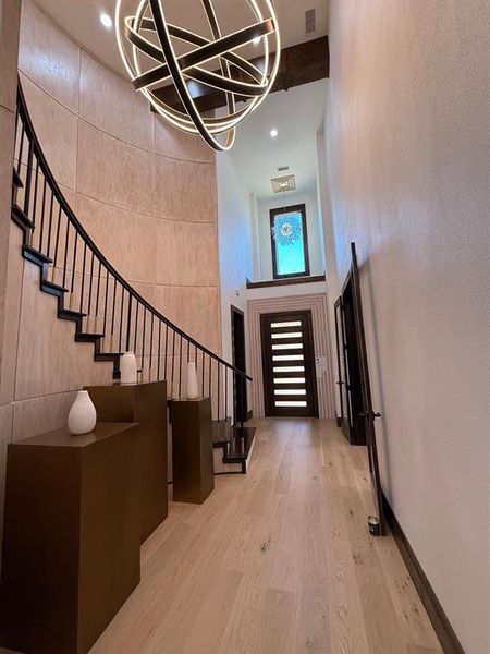 Entrance foyer with light wood-type flooring, stairs, and a high ceiling