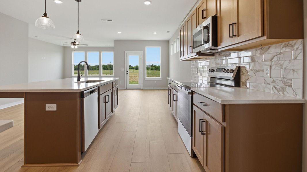 Kitchen with quartz countertops, tile backsplash, and view of gathering room Kitchen with quartz countertops, tile backsplash, and view of gathering room