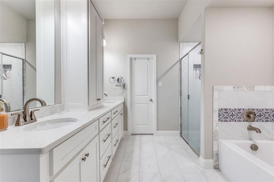 Full bath featuring a garden tub, a shower stall, double vanity, and light marble finish flooring Full bath featuring a garden tub, a shower stall, double vanity, and light marble finish flooring