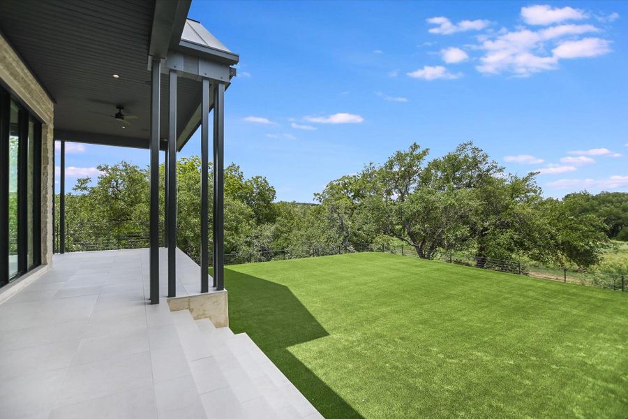 An inviting covered patio overlooks a generous green yard, perfect for outdoor enjoyment and relaxation.