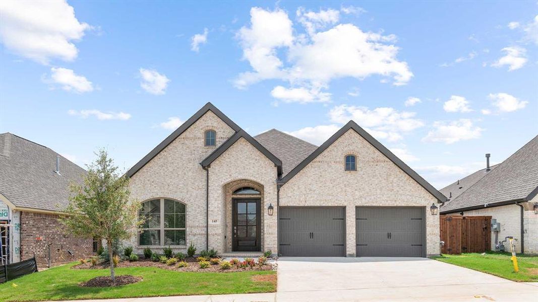 French country home with a garage and a front yard