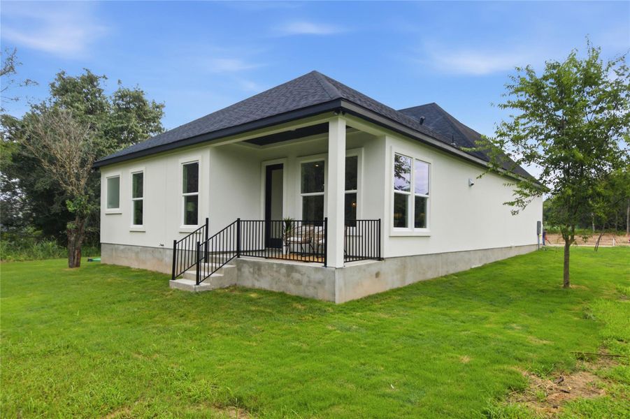 A contemporary residence with a welcoming covered patio, set amidst a vibrant green lawn.