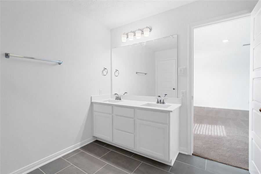 This stunningly updated primary bathroom is truly move-in ready! It features white stained cabinetry with light countertops, dual sinks, a large mirror, high ceilings, custom paint, and sleek modern finishes throughout.
