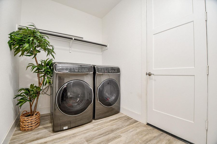 This spacious laundry room boasts a modern, sleek white interior, vinyl plank flooring, and a convenient storage shelf. This spacious laundry room boasts a modern, sleek white interior, vinyl plank flooring, and a convenient storage shelf.