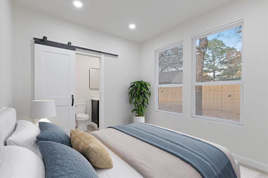 Bedroom featuring a barn door and ensuite bath