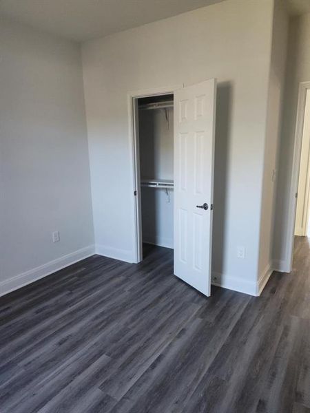 Unfurnished bedroom featuring dark wood-type flooring and a walk in closet Unfurnished bedroom featuring dark wood-type flooring and a walk in closet
