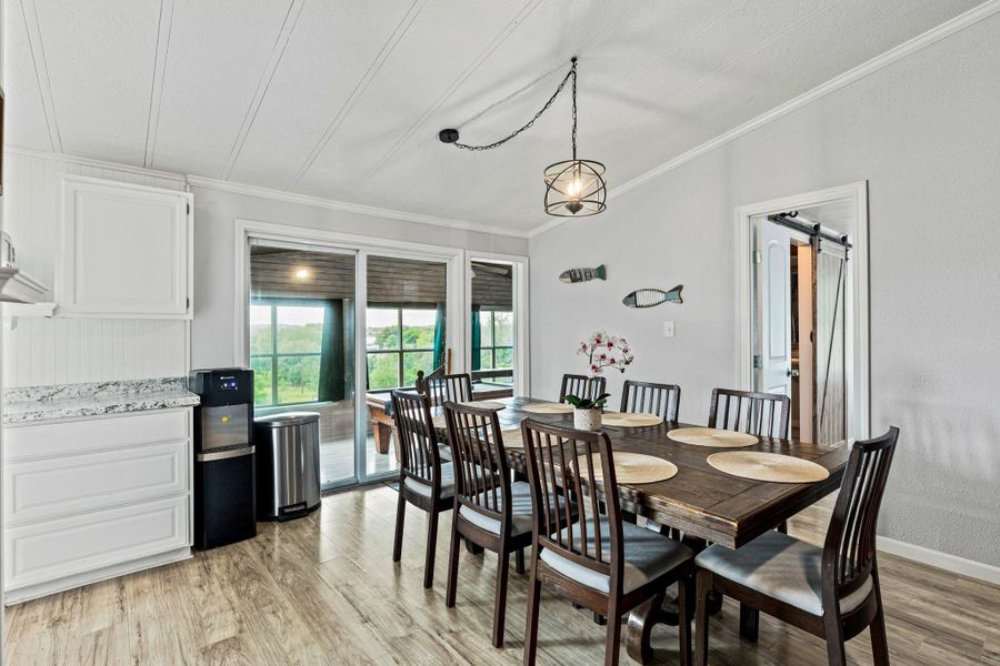 Dining area featuring wood-finish flooring, a contemporary wire-cage pendant light, and a white beadboard ceiling