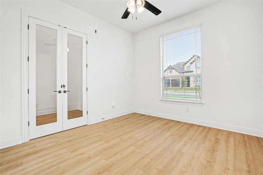 Unfurnished bedroom featuring french doors, light wood finished floors, a closet, and a ceiling fan