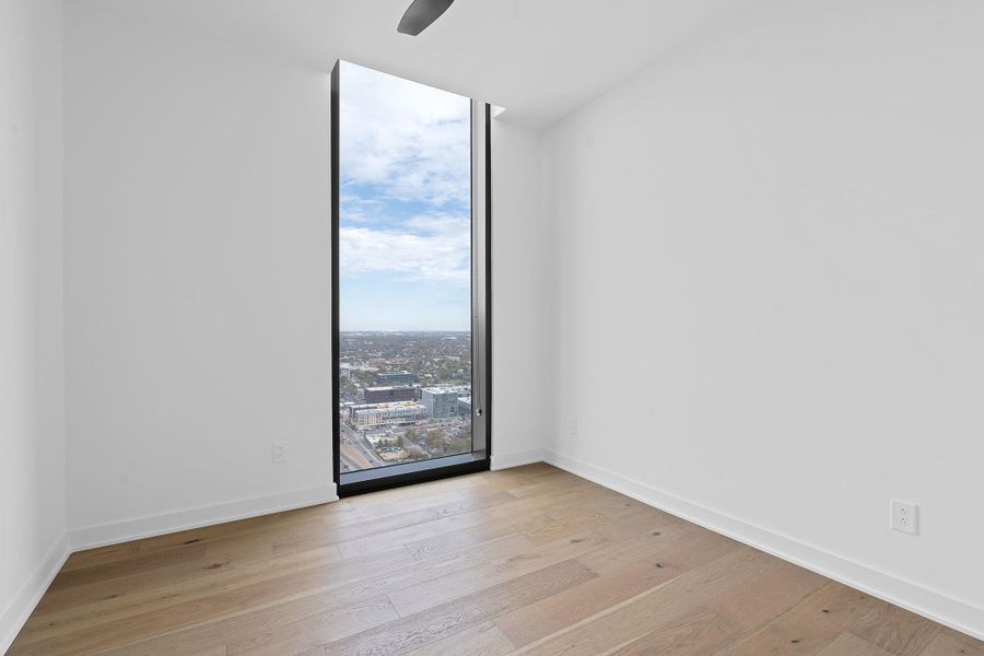 Room with a wall of windows, light wood finished floors, and a city view