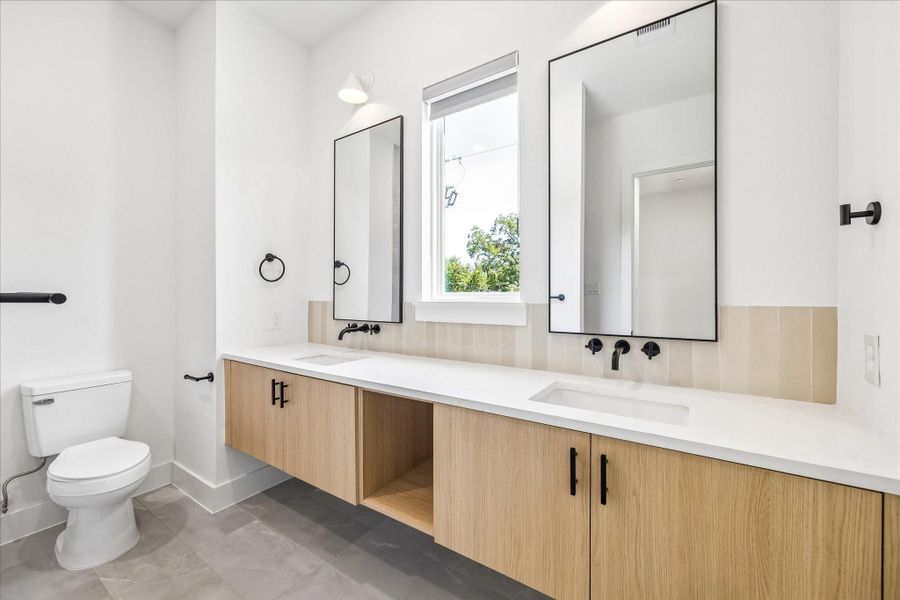 Warm wood cabinetry, matte black fixtures, and quartz countertops continue the home’s cohesive designer aesthetic.