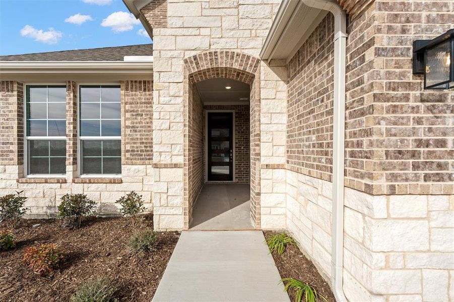 Doorway to property with stone siding and brick siding