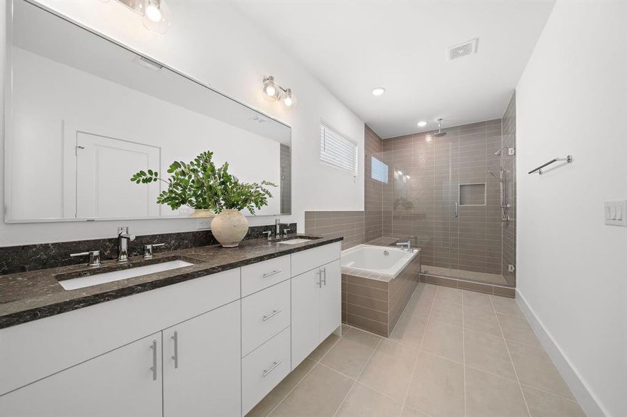 Primary suite bathroom has two sinks, a huge soaking tub and a large glass shower with a bench built inside.