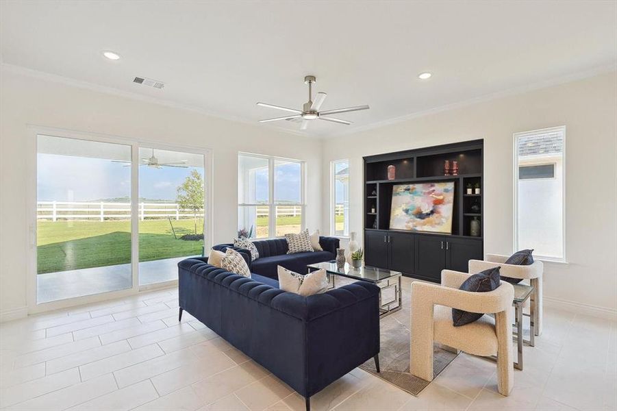 Living room with crown molding, ceiling fan, and light tile floors