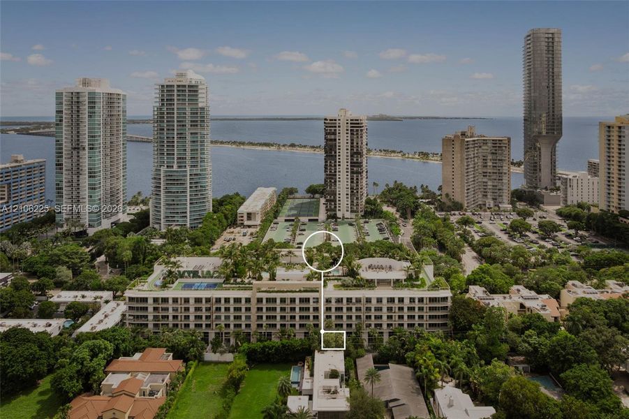 Aerial perspective of a multi-story residential building featuring rooftop recreational facilities, landscaped gardens, multiple tennis courts, and mature perimeter trees Aerial perspective of a multi-story residential building featuring rooftop recreational facilities, landscaped gardens, multiple tennis courts, and mature perimeter trees