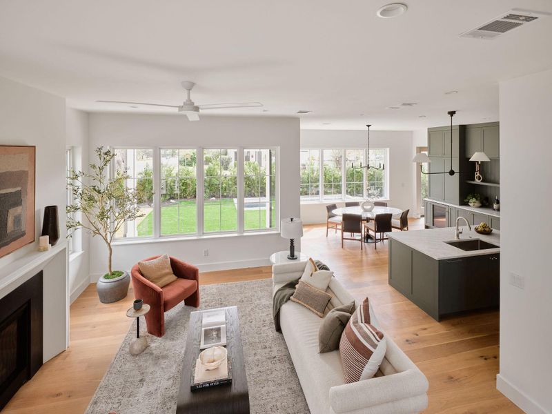 Living area with plenty of natural light, light wood-type flooring, and a ceiling fan Living area with plenty of natural light, light wood-type flooring, and a ceiling fan