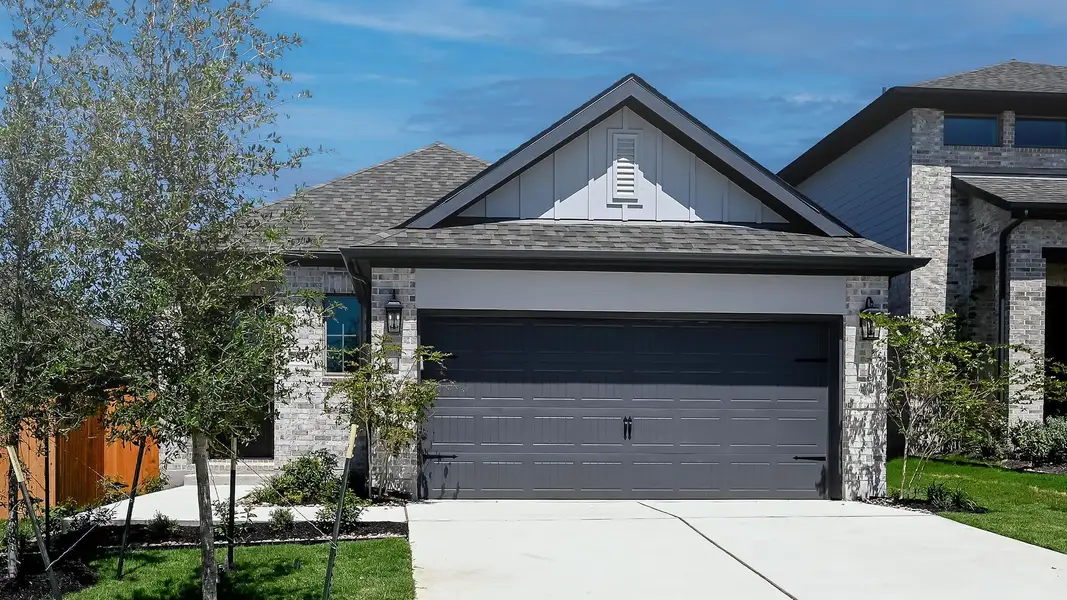 View of front of property with board and batten siding, a shingled roof, an attached garage, driveway, and brick siding View of front of property with board and batten siding, a shingled roof, an attached garage, driveway, and brick siding