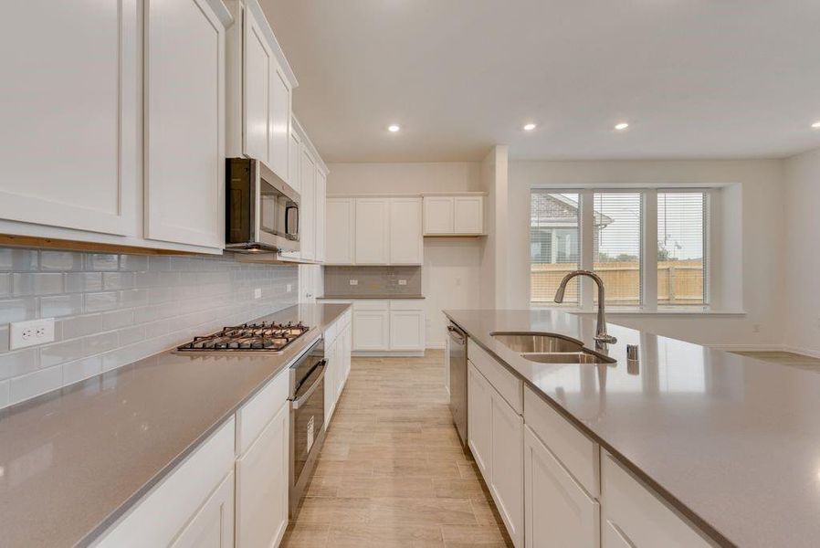 Kitchen featuring white cabinetry, light wood-type flooring, backsplash, stainless steel appliances, and sink