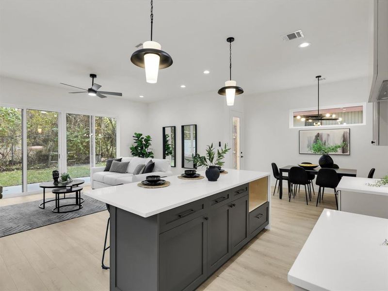 Kitchen featuring decorative light fixtures, light wood-type flooring, and ceiling fan with notable chandelier