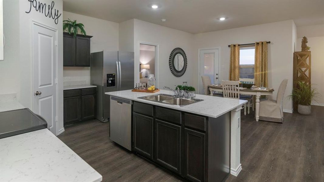 Kitchen with dark wood-style flooring, an island with sink, stainless steel appliances, recessed lighting, and light stone counters