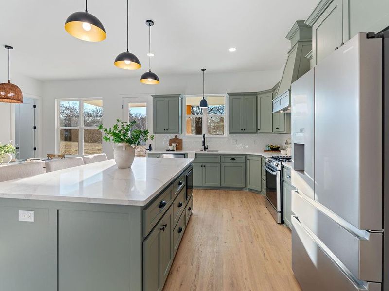 Kitchen featuring white refrigerator with ice dispenser, light stone counters, light wood-type flooring, gas range, and green cabinets