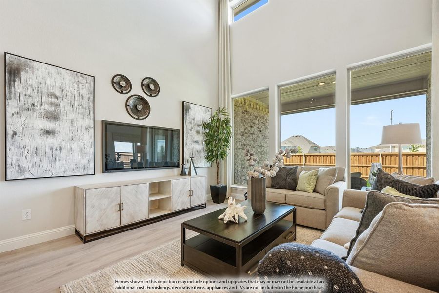 Living room with two-story ceiling, large windows, wall-mounted TV, and neutral furniture on light hardwood floors