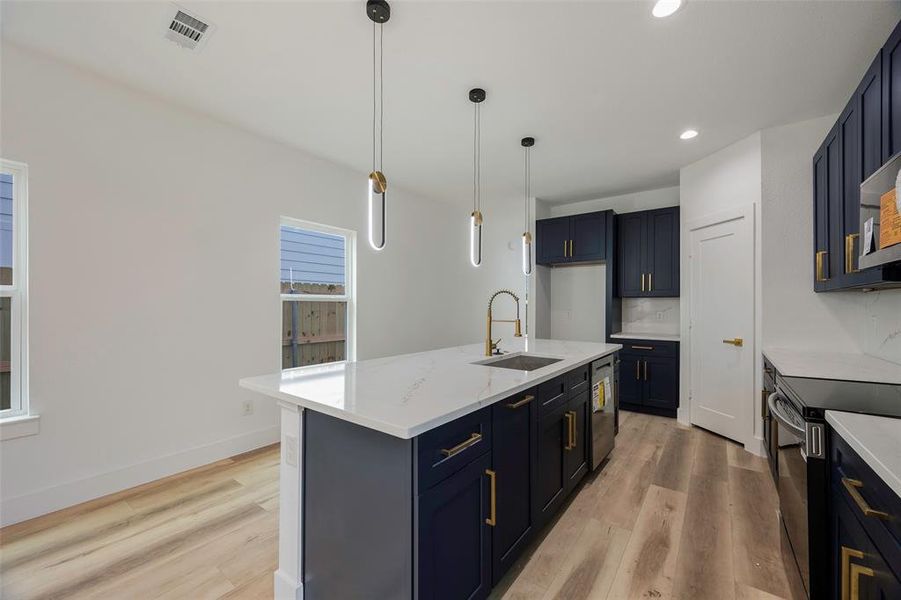 Kitchen with sink, pendant lighting, an island with sink, range with electric cooktop, and light hardwood / wood-style floors