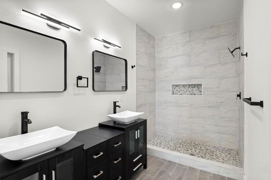 Bathroom featuring a walk in shower, double vanity, and wood tiled floors
