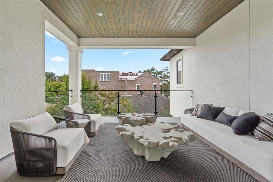 On the second floor, a spacious balcony offers a serene outdoor retreat, perfect for relaxing or entertaining. The wood-paneled ceiling adds warmth and sophistication, while the glass railing provides unobstructed views of the surrounding neighborhood.