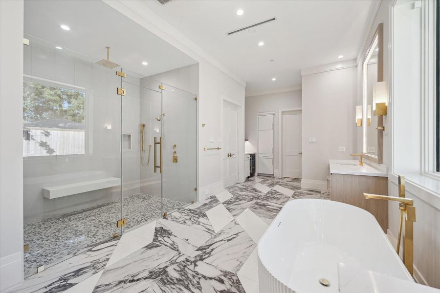 A stunning frameless glass shower with a floating bench and three showerheads anchors the space, while a dedicated dry-bar area with a morning bar fridge completes this luxurious retreat.