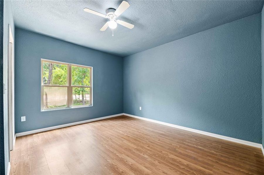 Unfurnished room with hardwood / wood-style floors, ceiling fan, and a textured ceiling Unfurnished room with hardwood / wood-style floors, ceiling fan, and a textured ceiling