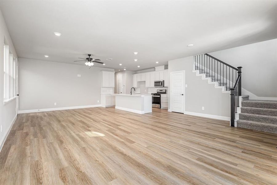 Unfurnished living room featuring stairs, light wood-type flooring, a ceiling fan, and recessed lighting