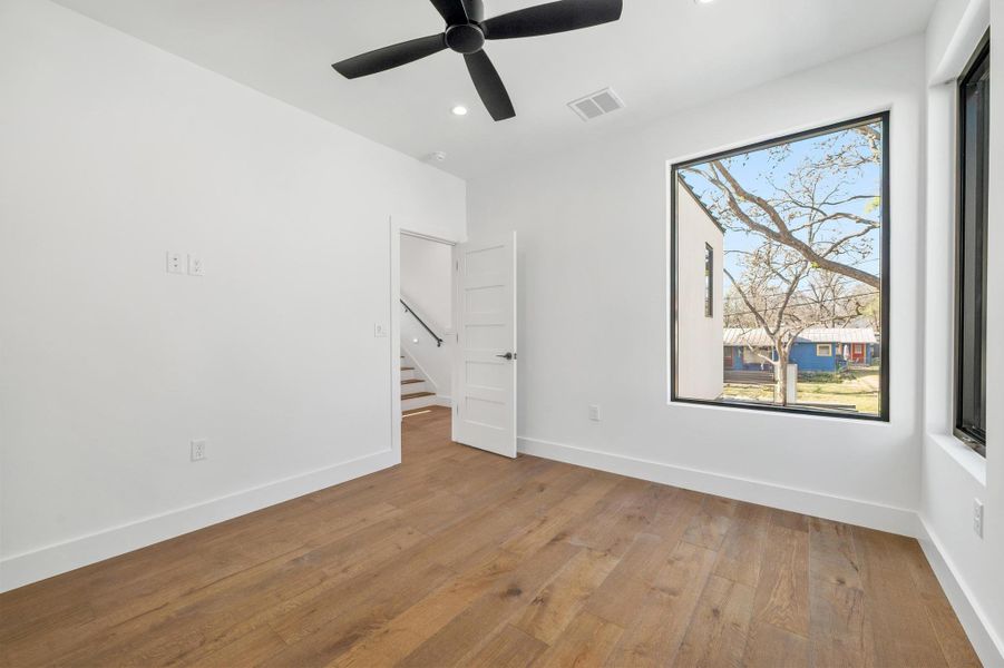 Unfurnished room with baseboards, visible vents, wood-type flooring, and ceiling fan