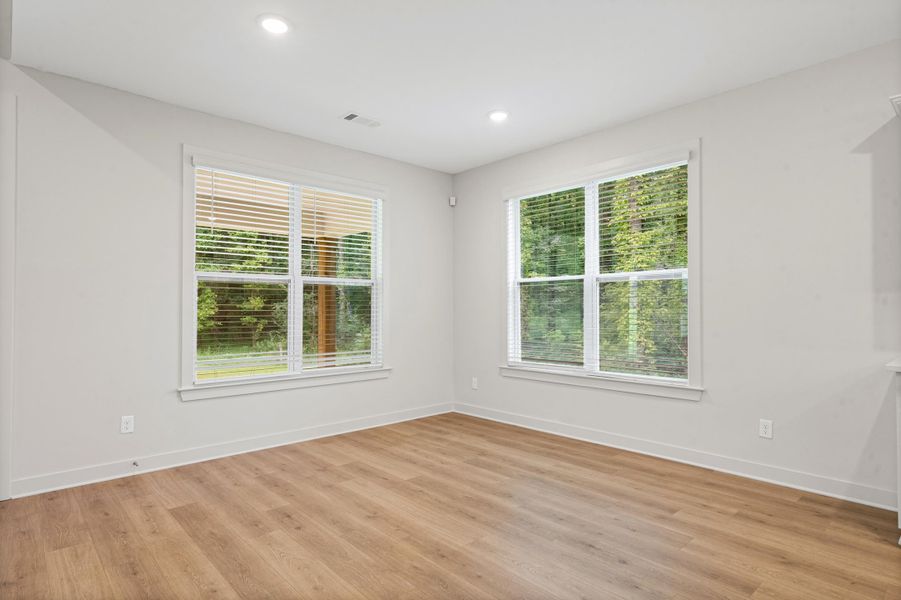 Room featuring two expansive windows with blinds, wood-finish flooring, recessed lighting, and white baseboards Room featuring two expansive windows with blinds, wood-finish flooring, recessed lighting, and white baseboards