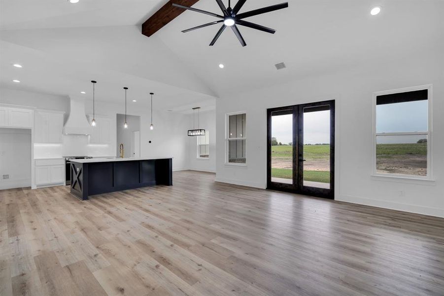 Unfurnished living room with french doors, high vaulted ceiling, light hardwood / wood-style flooring, and beam ceiling