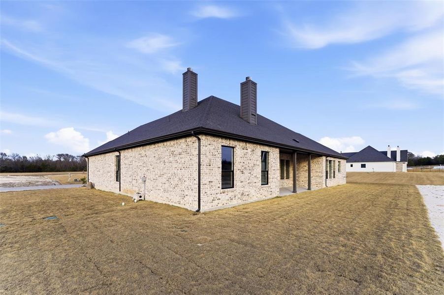 Back of property with a lawn, a chimney, a patio area, and brick siding