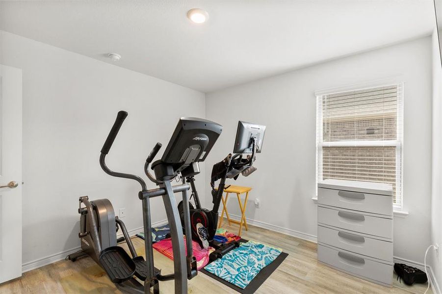 Workout room with baseboards and light wood-type flooring