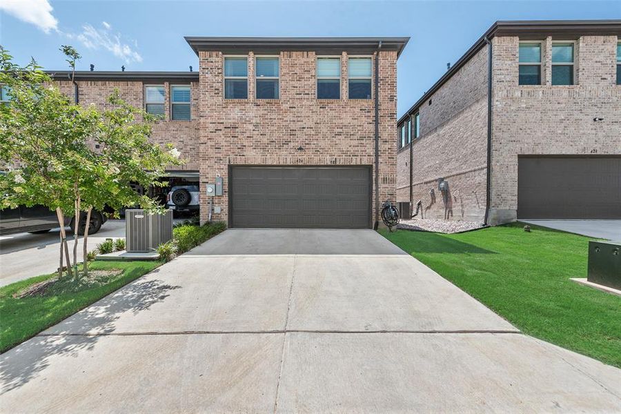 Brick facade residence with an integrated two-car garage featuring a dark gray door Brick facade residence with an integrated two-car garage featuring a dark gray door