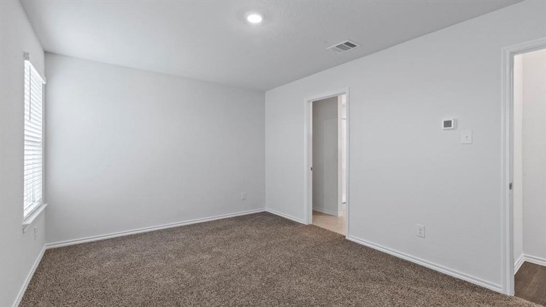 Unfurnished bedroom featuring dark colored carpet and baseboards