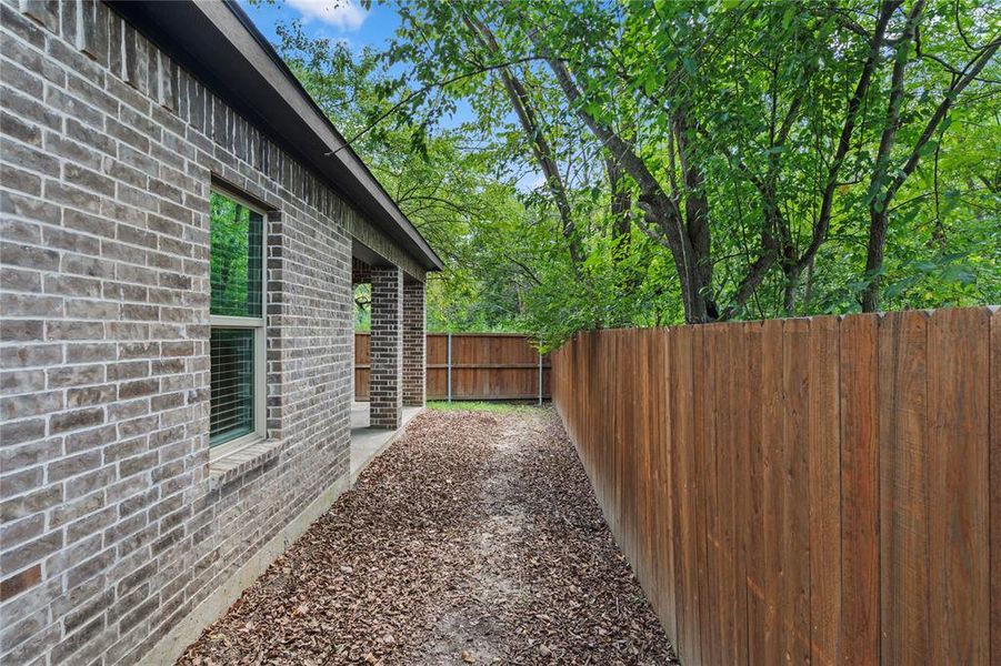 View of side of property with brick siding, a fenced backyard, and a patio View of side of property with brick siding, a fenced backyard, and a patio