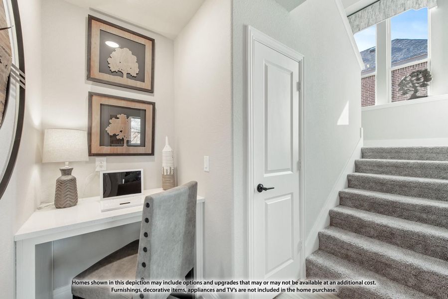 Built-in desk nook with white cabinetry and wall art next to carpeted staircase and white door