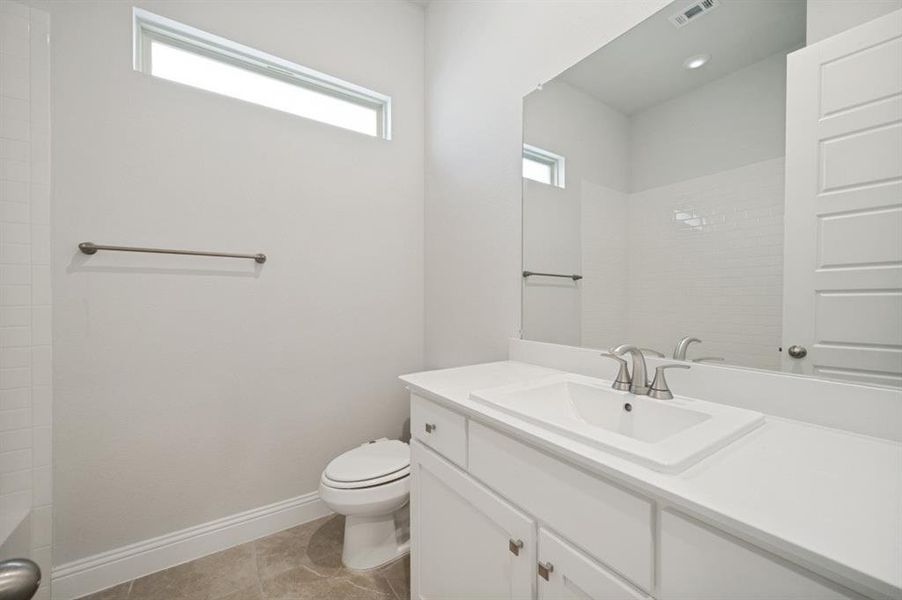 Bathroom featuring a white vanity with an integrated sink, brushed nickel faucet, large mirror, and tiled flooring
