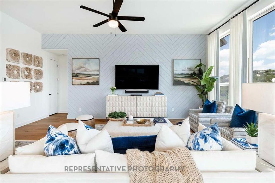 Living area featuring wood finished floors, an accent wall, ceiling fan, and wooden walls Living area featuring wood finished floors, an accent wall, ceiling fan, and wooden walls