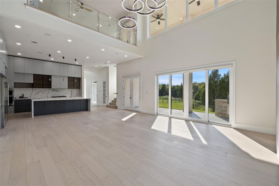 Unfurnished living room with a towering ceiling and light wood-type flooring