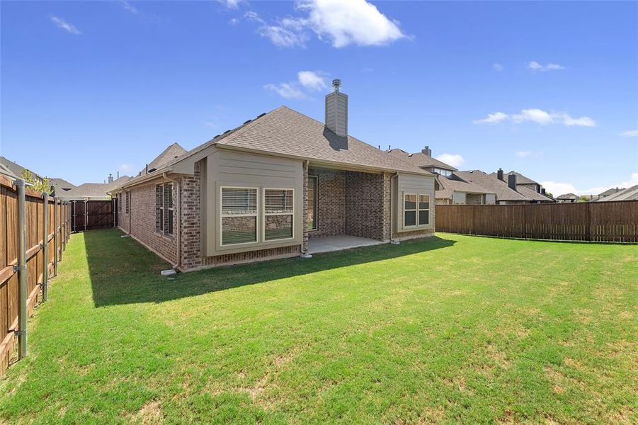 Back of property with a patio, a fenced backyard, and brick siding Back of property with a patio, a fenced backyard, and brick siding