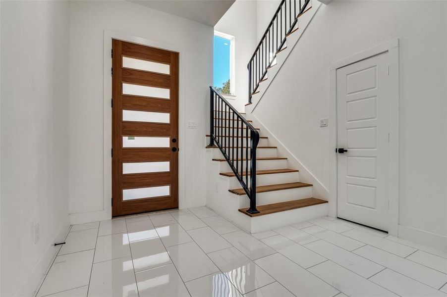Foyer with light tile patterned floors and stairs
