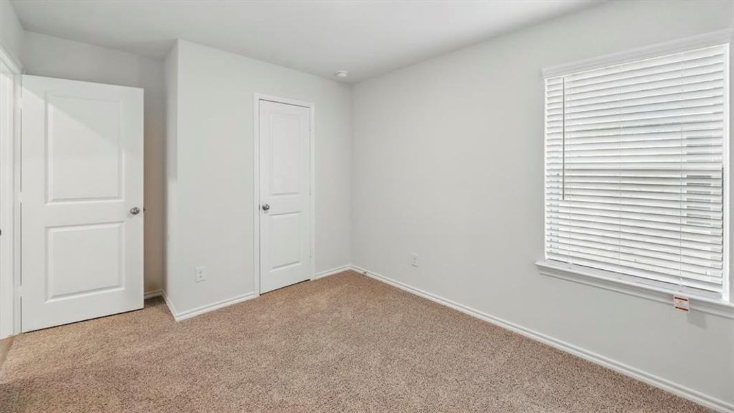 Neutral-toned carpeted room featuring white walls and a window with horizontal blinds
