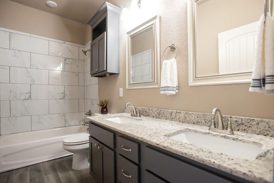 Bathroom featuring double vanity, wood finished floors, and shower / bathtub combination Bathroom featuring double vanity, wood finished floors, and shower / bathtub combination